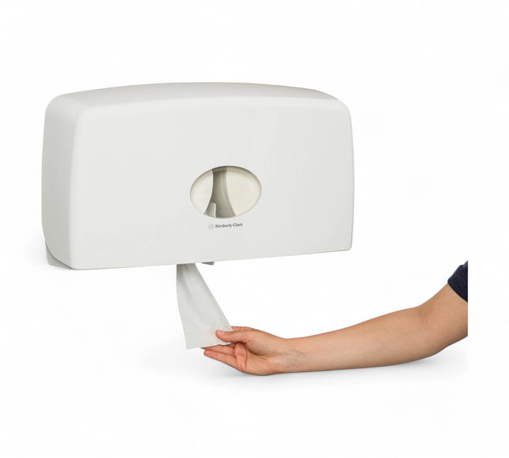 Side-view of a KIMBERLY-CLARK PROFESSIONAL AQUARIUS Twin Jumbo Roll Dispenser (70210) mounted on a wall, with a hand pulling tissue from the bottom opening.
