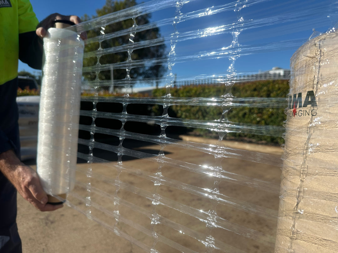 Person wrapping pallet using clear ventilated hand stretch film