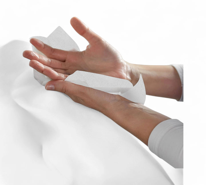 Hands wiping with a white KLEENEX VIVA kitchen towel sheet, demonstrating absorbency and softness on a plain white background