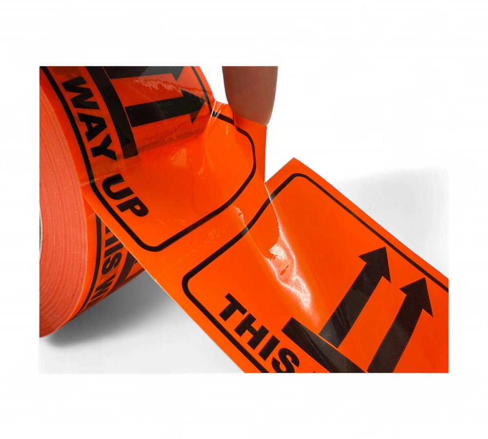 Close-up of perforated This Way Up warning labels in bold black print on fluro orange background with upward arrow icons